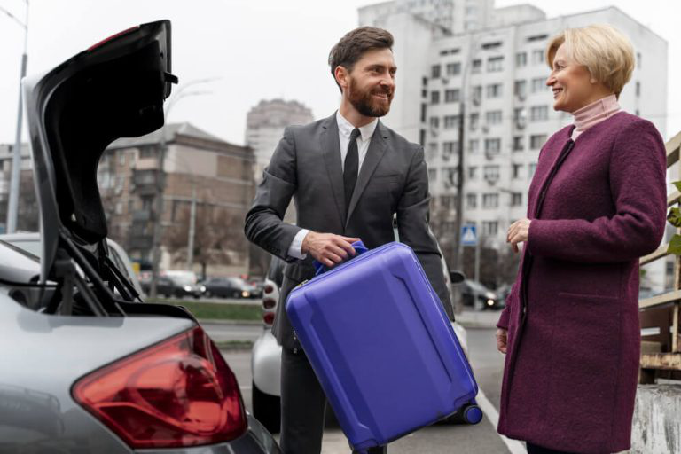 Professional chauffeur loading a stylish purple suitcase into the trunk of a luxury vehicle, with a satisfied client standing by.